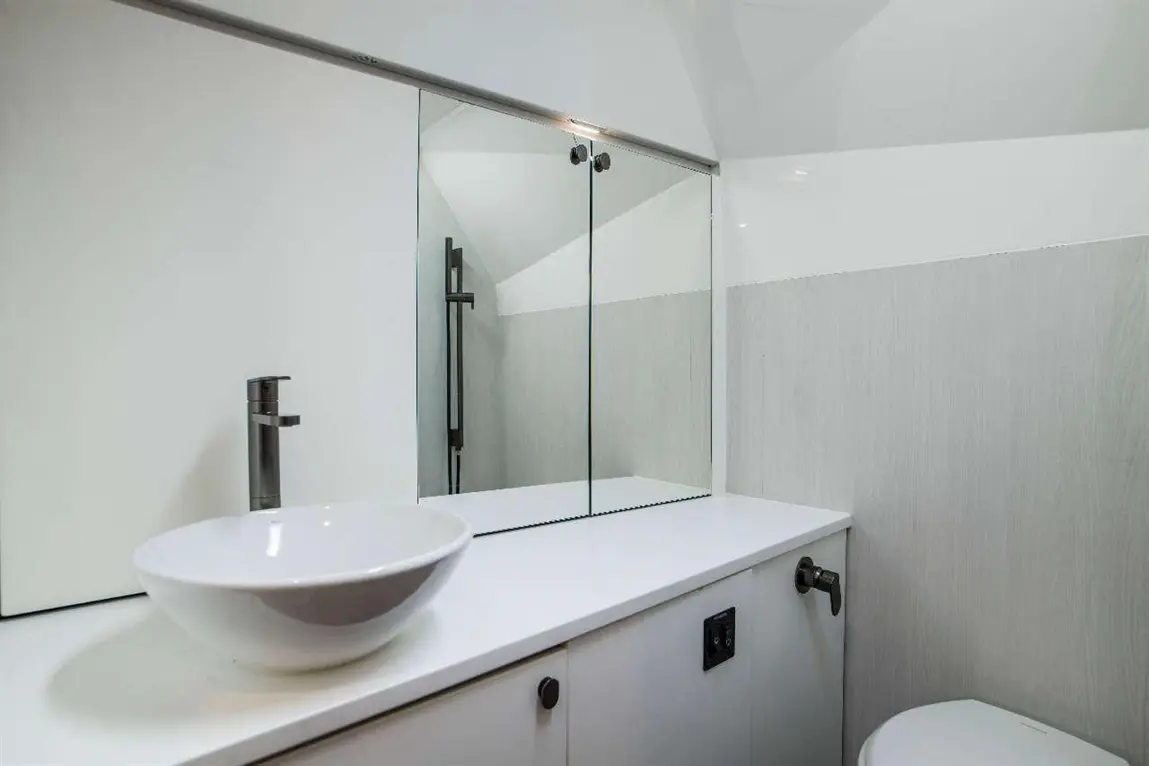 Modern bathroom featuring a white bowl sink, sleek tap, and a large mirror reflecting minimalistic design elements.